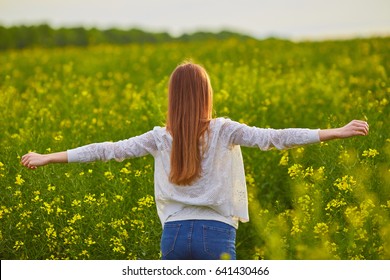 Joyful girl at yellow rape seed meadow