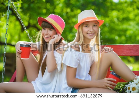 Joyful girlfriends having fun on swing outdoor. Friendship concept