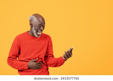 Joyful glad elderly man in a red sweater laughs while looking at a smartphone, hand on stomach, standing against a vibrant yellow background, signifying good news or a joke - Powered by Shutterstock