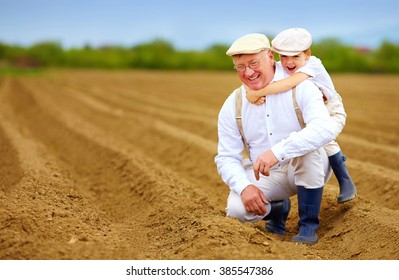 Joyful Grandpa And Grandson Having Fun On Spring Plowed Field