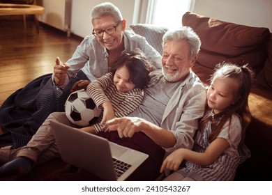 Joyful Grandparents with Grandchildren Watching Soccer Game on Laptop at Home - Powered by Shutterstock