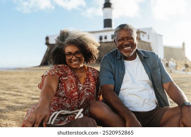 Joyful grandparents posing near a historic lighthouse in Salvador, embracing the warmth of a sunny coastal vacation. Perfect for concepts of family, relaxation, and travel. - Powered by Shutterstock