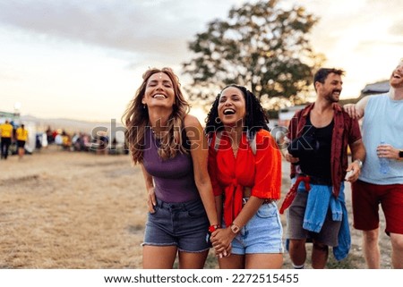 A joyful group of friends are at a summer day festival having a fun time together enjoying a nice day.
