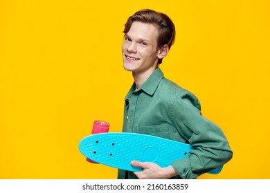 joyful guy with a skateboard stands on a yellow background - Shutterstock ID 2160163859
