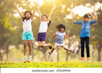 Joyful Happy Asian Family Jumping Together At Outdoor Park