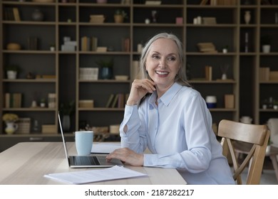 Joyful Happy Pretty Elderly Freelance Businesswoman Looking Away From Table With Laptop, Smiling, Laughing, Sitting At Work Desk, Using Laptop, Paper Documents. Candid Female Portrait