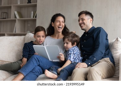 Joyful Happy Two Generations Full Family Laughing At Funny Story, Reading Book At Home. Happy Young Hispanic Couple Parents Involved In Domestic Hobby Activity With Small Children Son Daughter.