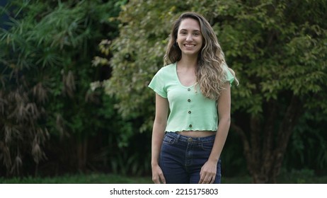 Joyful Hispanic Latina Girl Standing Outside Smiling. Young Woman Latina Portrait. Millennial 20s Female Person In Tracking Shot.