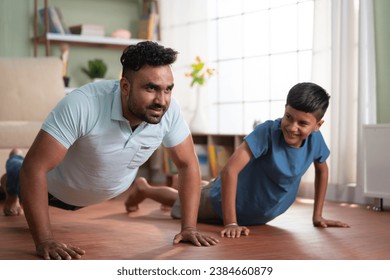 Joyful indian father with son doing push ups exercise at home - concept of Joyful fitness, Active lifestyle and healthy habits - Powered by Shutterstock