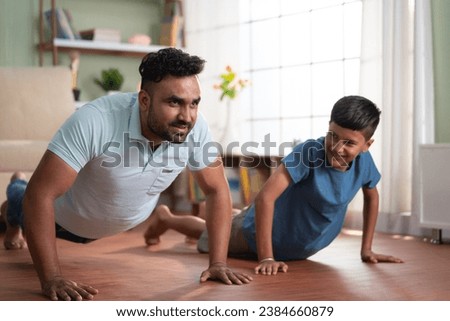 Joyful indian father with son doing push ups exercise at home - concept of Joyful fitness, Active lifestyle and healthy habits