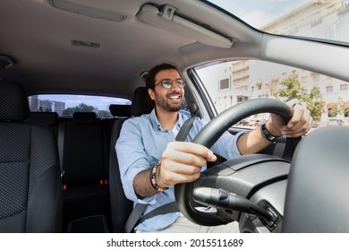 Joyful indian man driving car, shot from dashboard, going on trip during summer vacation, copy space. Happy middle-eastern guy in casual outfit and glasses driving his brand new nice car - Shutterstock ID 2015511689