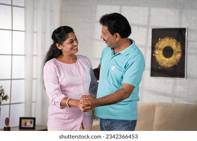 Joyful indian middle aged couple dancing together by holding hands at home - concept of Affectionate Bonding, Romantic Dance and Happy Life. - Powered by Shutterstock