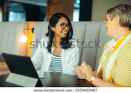 A joyful interaction between a professor and PHD student sharing ideas and conversation in a comfortable cafe setting.