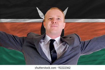 Joyful Investor Spreading Arms After Good Business Investment In Kenya, In Front Of Flag