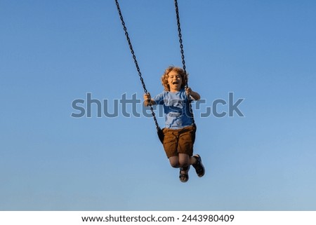 Joyful kid swinging on a swing. Happiness children. Child extreme swinging. Danger high Swing in sky. Craziness and freedom. Kid playing on swing-set outdoor. Playful child swinging very high to the