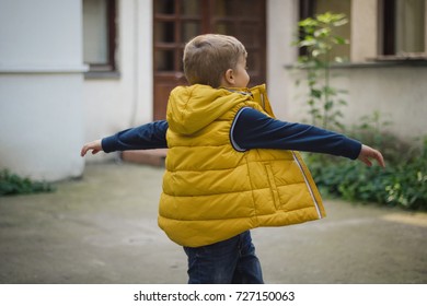 Joyful Kid Turning Around While Playing Outdoors. Carefree Boy Spinning Out Of Joy.