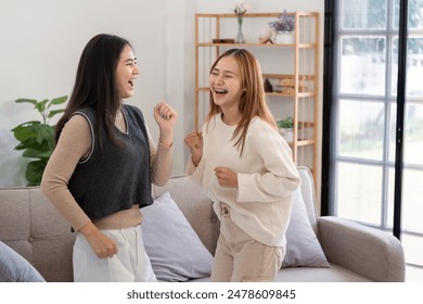 Joyful Lesbian Couple Dancing Together in Modern Living Room with Natural Light and Cozy Decor - Powered by Shutterstock