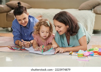 Joyful lesbian couple   their little daughter coloring pictures together