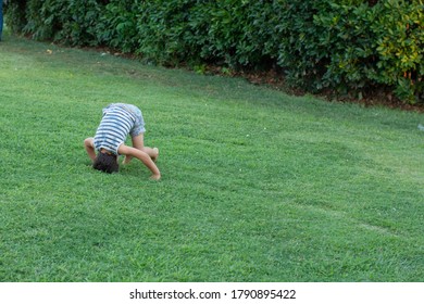 A Joyful Little Boy Is Somersault On The Grass