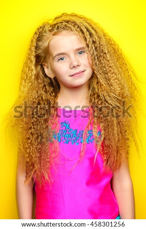 Joyful little girl with beautiful blonde hair over yellow background. Kid's style. Hairstyle.