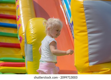 Joyful little girl jumping on an inflatable trampoline. - Shutterstock ID 2099713003