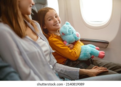 Joyful Little Girl And Woman Sitting In Passenger Airplane