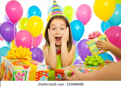 Joyful little kid girl receiving gifts at birthday party. Holidays, birthday concept. 