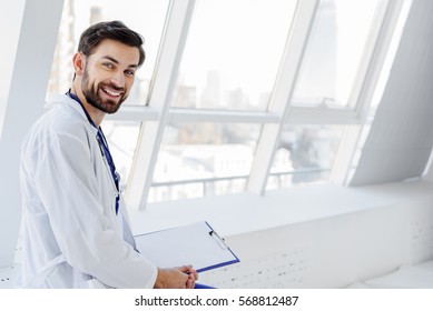 Joyful Male General Practitioner Relaxing Near Window