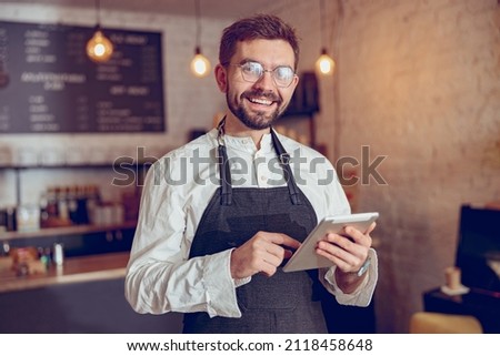 Joyful male worker using tablet computer in cafe