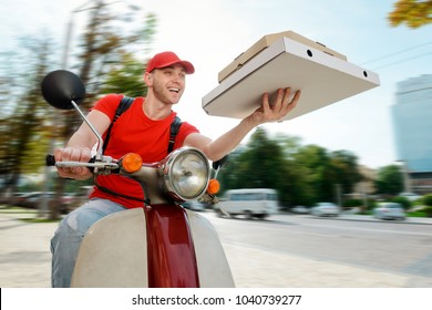 Joyful Man Is Delivering Pizza. Deliveryman Uses A Company Motorbike To Reach A Customer. Order Fast Food Online.