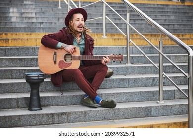 Joyful man with dreadlocks playing music outdoors