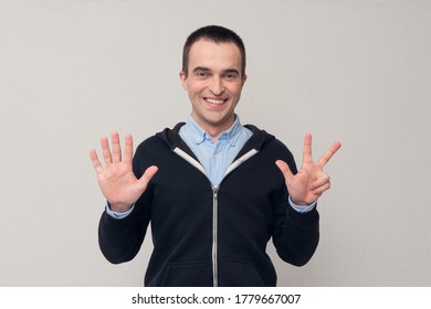 Joyful man shows fingers eight, white background. Concept of emotions and feelings