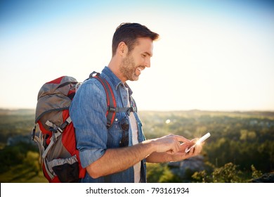 Joyful Man Using Phone To Check Map During Hiking Trip