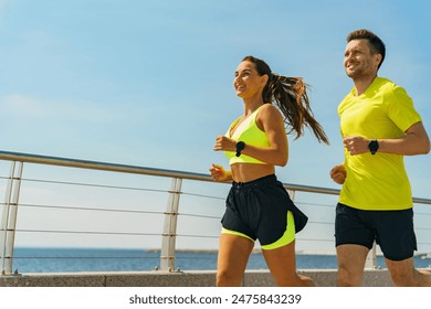 Joyful man and woman run along a seaside path, basking in the morning sun's warmth and energy. - Powered by Shutterstock