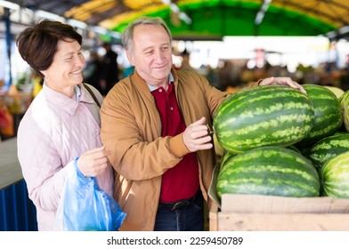 Joyful mature couple choosing local watermelon while - Powered by Shutterstock