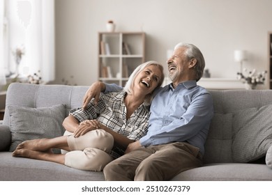 Joyful mature wife and husband resting together on couch, hugging, talking and laughing enjoy time together, joking, having fun, relish their harmonic relations, understanding and joint sense humour - Powered by Shutterstock