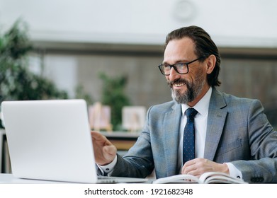 Joyful middle aged businessman is using laptop, having online conference. Successful male employee talking by video call with colleagues, discussing ideas - Powered by Shutterstock