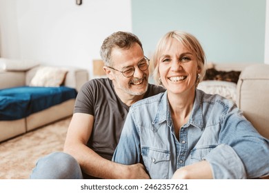 Joyful middle-aged couple laughing and smiling, enjoying quality time together at home, showcasing love and happiness. - Powered by Shutterstock