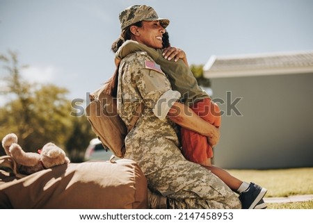 Joyful military mom embracing her son after returning home from the army. Courageous female soldier reuniting with her young child after serving in the military.