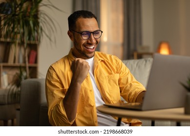 Joyful millennial black man with laptop celebrating online win or work success at home. Excited young African American guy enjoying big sale in web store, gambling on internet - Powered by Shutterstock