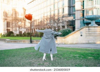 A joyful moment of a woman twirling with a heart-shaped balloon in a vibrant urban park during golden hour - Powered by Shutterstock