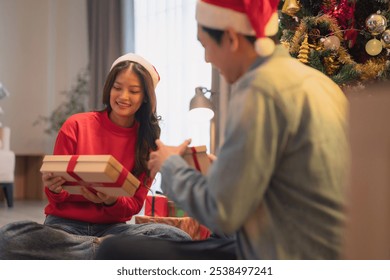 Joyful moments are shared as couple exchanges gifts during festive Christmas season, surrounded by beautifully decorated tree and warm holiday spirit. - Powered by Shutterstock