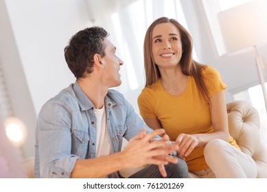 Joyful mood. Beautiful smiling young woman looking happy while sitting on the sofa and discussing exciting plans for the future with her beloved man - Shutterstock ID 761201269