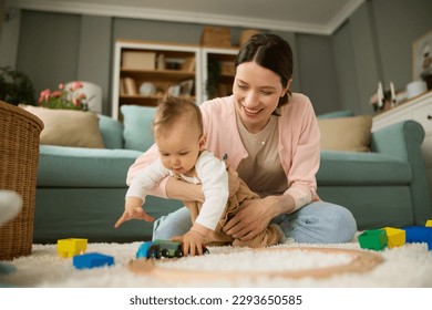 Joyful mother and baby boy playing with toys on a carpet at home - Powered by Shutterstock