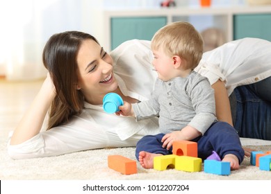 Joyful mother and baby playing with toys on a carpet at home