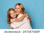 Joyful mother and daughter embracing with smiles on a vibrant blue background, expressing love and happiness together