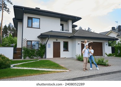 Joyful mother and daughter on father's shoulders in front of modern townhouse - Powered by Shutterstock