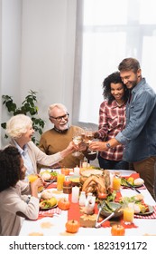 Joyful Multicultural Family Clinking Wine Glasses During Thanksgiving Dinner