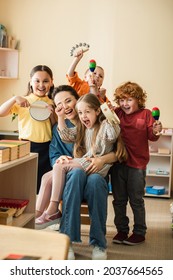 Joyful Multiethnic Kids With Teacher Playing Musical Instruments In Classroom