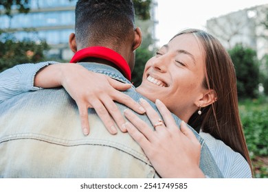 Joyful multiracial Couple Sharing Tender Outdoor Embrace as Young Woman with Radiant Smile Hugs Her Boyfriend in Park Two people embracing each other. Emotional union and relationship. High quality - Powered by Shutterstock